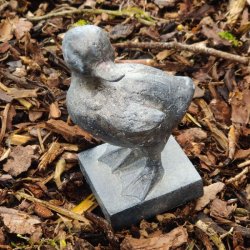 N�rbillede af en �lling-figur i farven antique kul, st�ende udend�rs p� et naturligt underlag af tr�flis.