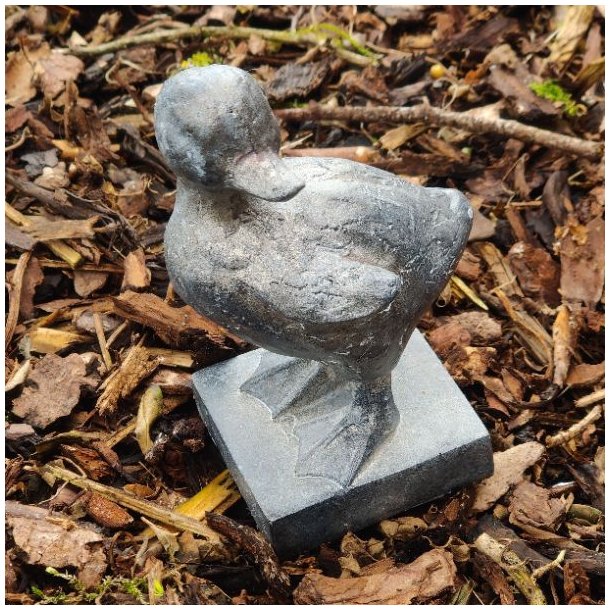 N�rbillede af en �lling-figur i farven antique kul, st�ende udend�rs p� et naturligt underlag af tr�flis.