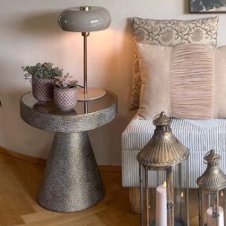 Hyggeligt hj�rne med en moderne bordlampe, m�nstrede puder i beige nuancer og rustikke lanterner p� et dekorativt metalbord.