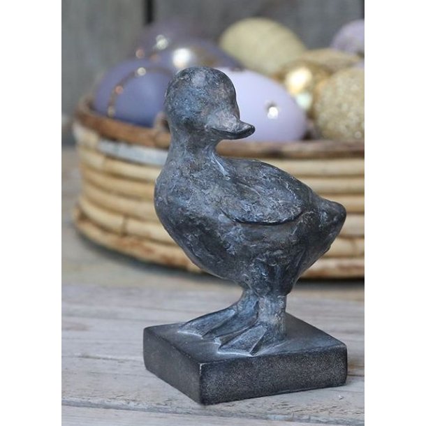 En naturtro �lling-figur i polyresin med antique kul finish, placeret foran en kurv med p�ske�g i st�rrelsen H12,5 cm.