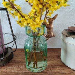 Gr�n rillet glasvase med en gul forsythiagren og en lille bronzefarvet p�skehare i kanten.