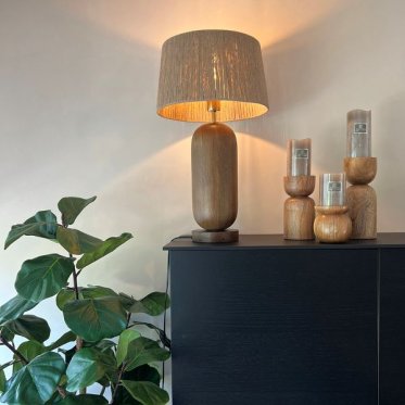 hyggelig-bordlampe-nordisk-styling-stue-vindueskarm.jpg: En t�ndt retro-bordlampe med gr�nt glas og paddehat-form st�r p� en tr�-vindueskarm i en stue, omgivet af stueplanter og en bog, og kaster et varmt, hyggeligt lys i skumringen.