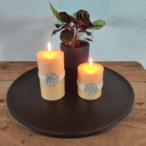 N�rbillede af to t�ndte gule bloklys med en lysere bund og m�rkere gul top, dekoreret med hvide b�nd og store rhinsten-blomster.