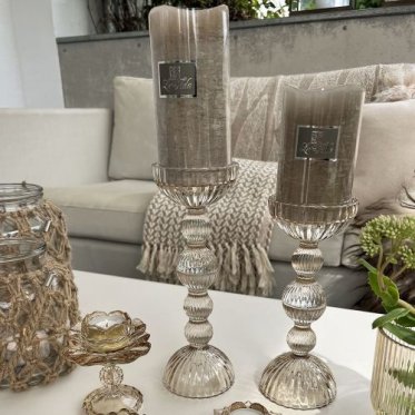 Elegante champagnefarvede glaslysestager i forskellige h�jder med store rustikke bloklys fra La Vida i en hyggelig stue med plaider.