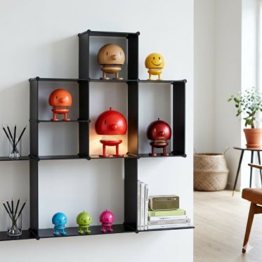 Et samlet, kvadratisk milj�billede med en moderne sort reol, der viser et udvalg af forskellige Hoptimister, inklusive tr�, Smiley, en r�d jubil�umsudgave og en t�ndt Hoptimist-lampe.