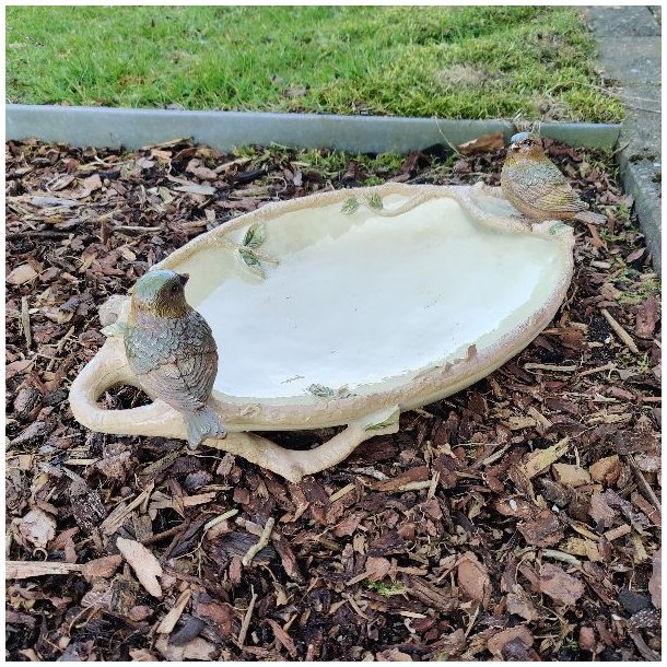 Fuglebadet i polyresin placeret i et havebed med barkflis, der fremh�ver de naturlige farver.