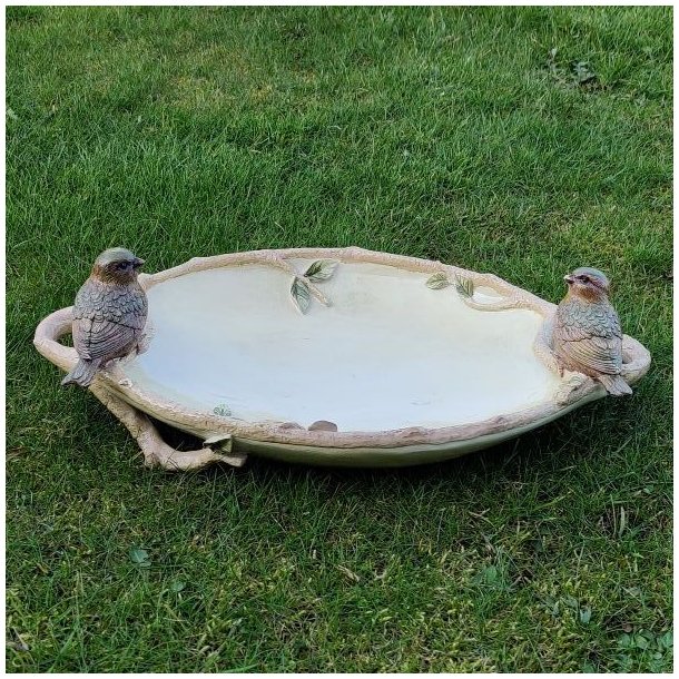 Dekorativt sandfarvet fuglebad med to fuglefigurer placeret p� en gr�n gr�spl�ne.