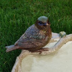 N�rbillede af en af de detaljerede fuglefigurer p� kanten af fuglebadet, der viser materialets struktur og farvenuancer.