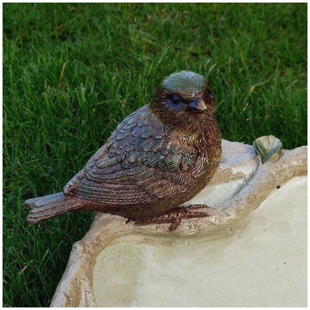 N�rbillede af en af de detaljerede fuglefigurer p� kanten af fuglebadet, der viser materialets struktur og farvenuancer.