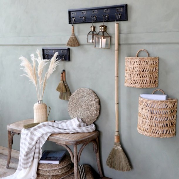 Billede af knager�kken stylet i en entr� foran en salviegr�n v�g, med to t�ndte messing-lanterner h�ngende fra knagerne og et str�-fejekost, i en rustik landstils-stemning.