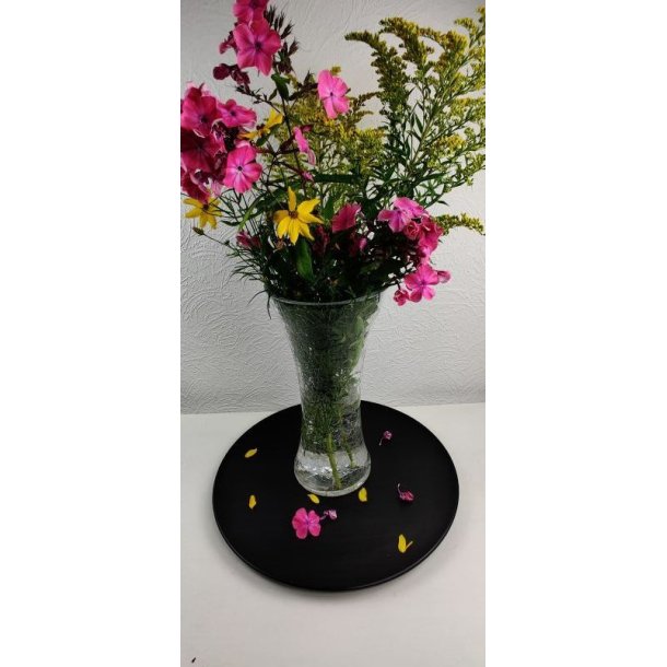 En stor, klar glasvase med krakeleret m�nster fyldt med vand og en sommerlig buket af lilla phlox og sm� gule blomster, placeret foran en hvid v�g med m�nstret tapet.