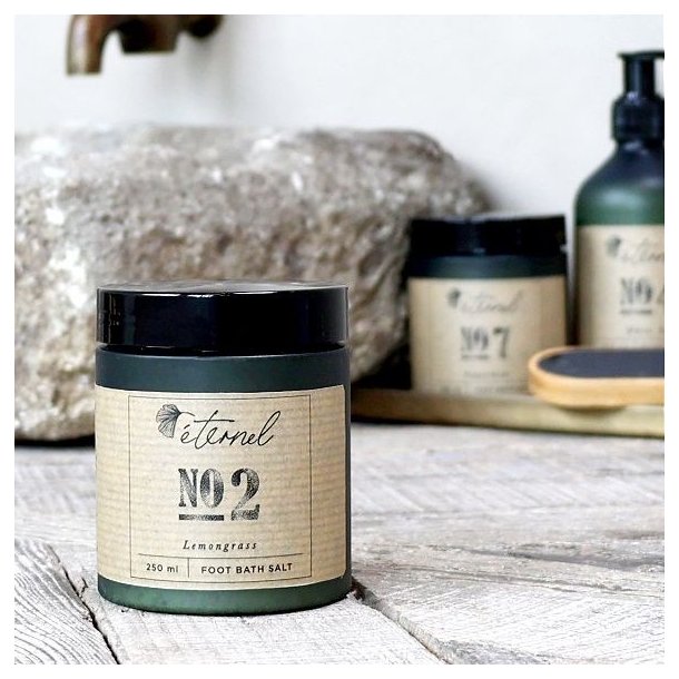 Eternel fodbadesalt opstillet i et badev�relsesmilj� ved siden af en stenvask, der illustrerer en luksuri�s spa-oplevelse.
