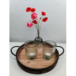 To gr�nne rillede fyrfadsstager i glas p� en rund tr�bakke med jernh�ndtag ved siden af en lille vase med r�de valmuer.
