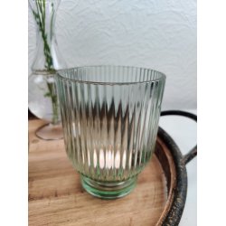 N�rbillede af en gr�n fyrfadstage i rillet glas placeret p� en rustik tr�bakke med t�ndt lys indeni.