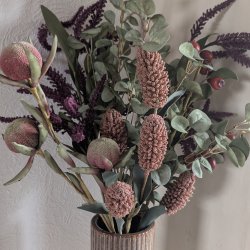 Kunstig-Blomstergren-Groenne-Blade-Buket-H�j-Vase Stor, fyldig buket med kunstige gr�nne grene, rosa og lilla evighedsblomster i en h�j, rillet keramikvase p� et opsatsbord.