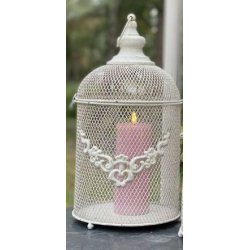 Milj�billede af det antik hvide lanternebur med et t�ndt rosa bloklys indeni. Lyset skinner hyggeligt gennem metalnettet i en udend�rs opstilling.