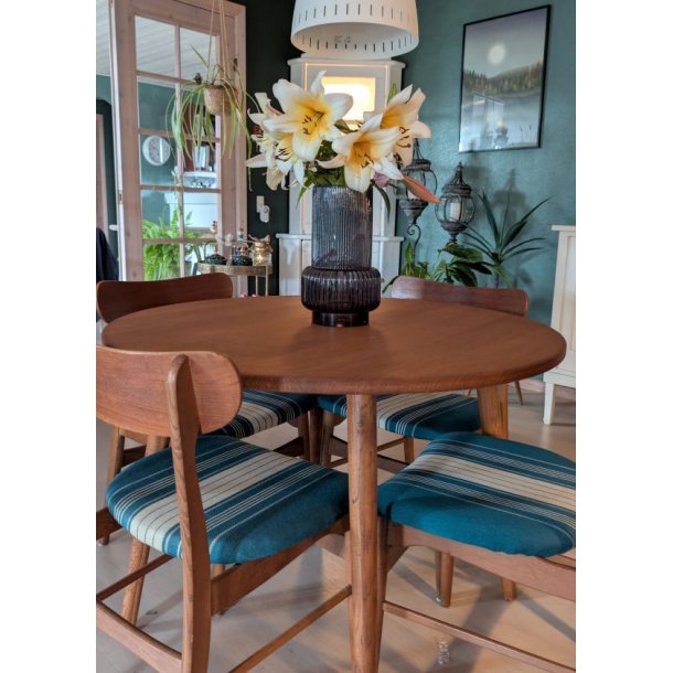 Stemningsbillede af m�rk rillet retro glasvase med liljer midt p� et rundt retro tr�spisebord i en stilfuld stue.