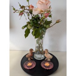 To rosa blomsterformede fyrfadsstager fra La Vida med t�ndte lys opstillet p� et sort fad med tr�fugle og en vase med lyser�de roser.