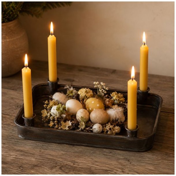 Jernfad med fire lysholdere pyntet til p�ske med gule stagelys, mos, p�ske�g og sm� blomster p� et tr�bord.