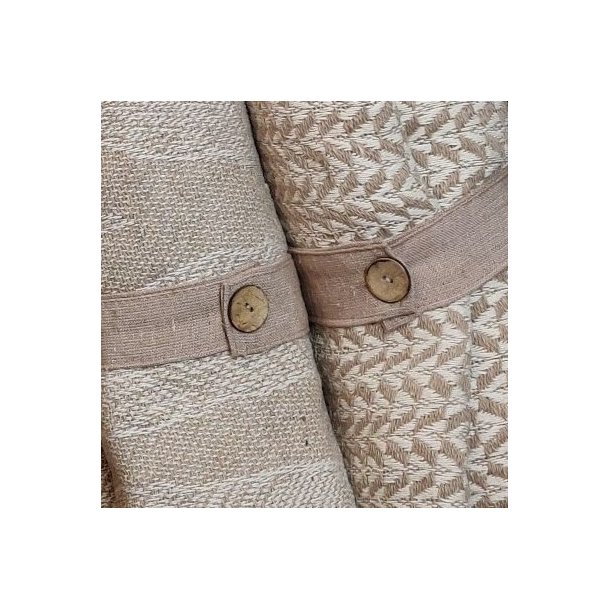 N�rbillede af det praktiske beige lukkeb�nd med en fin tr�knap, der holder den sammenrullede bomuldsplaid p�nt p� plads.