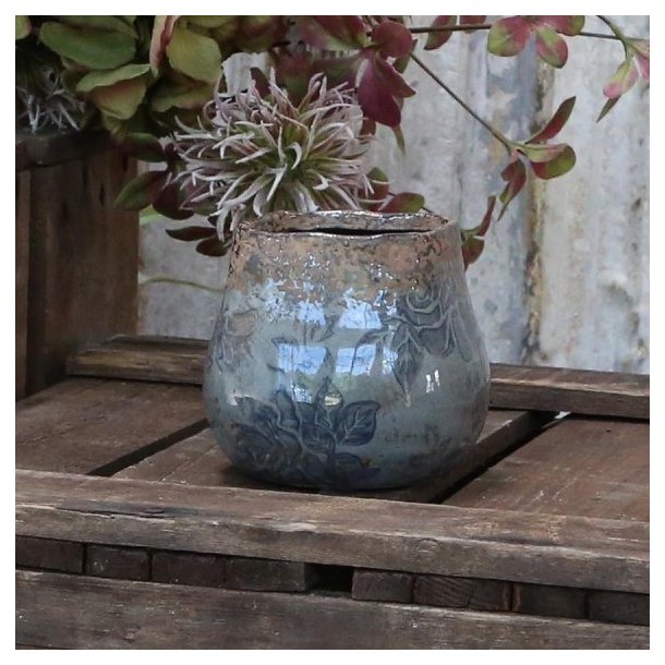 Bl� keramikvase fra Chic Antique med pr�get rose-m�nster og rustik topkant, opstillet p� en tr�bakke i et hyggeligt milj�.
