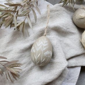 Dekorativt beige p�ske�g med hvidt bladm�nster h�ngende p� en for�rsgren i et lyst milj�.