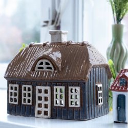 Stort bl�t keramikhus med brunt str�tag fra Det Gamle Apotek placeret i en lys vindueskarm ved siden af en vase med lavendler
