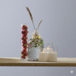 En fin Dew Drop lysk�de med 20 LED-lys p� s�lvtr�d er dekoreret omkring en glasvase med friske jordb�r og en flaske med gr�nne str� p� en tr�hylde Sammen med lysk�den ses tre hvide LED-bloklys i glas hvilket skaber en hyggelig og stemningsfuld belysning