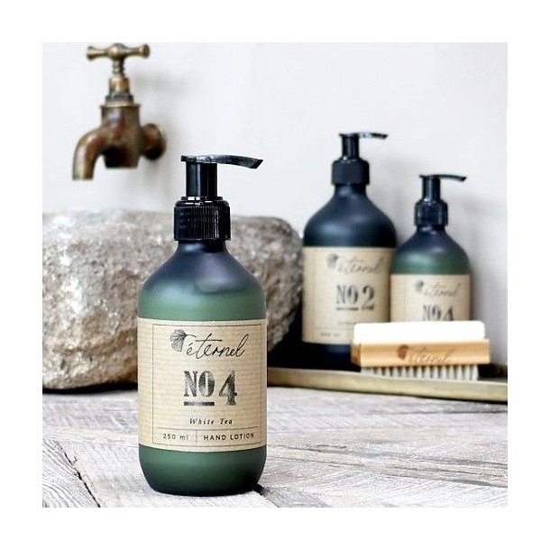 Eternel H�ndlotion No. 4 opstillet i et rustikt badev�relsesmilj� ved en vask, der fremh�ver produktets eksklusive design.