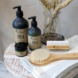 Milj�billede af Eternel plejeprodukter p� en tr�bakke, herunder negleb�rsten og h�rb�rsten, der viser produkternes naturlige sammenh�ng.