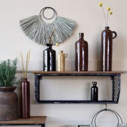 En stemningsfuld v�gdekoration med flere brune keramikflasker i forskellige st�rrelser placeret p� r� tr�hylder. Den mocca-brune flaske med h�ldetud ses her i en smuk kombination med naturmaterialer og gr�nne planter.