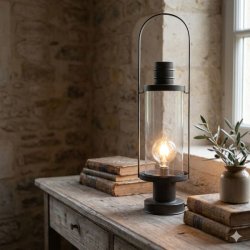 Et stemningsfuldt milj�billede, hvor den franske staldlanterne st�r t�ndt p� en rustik tr�kasse ved et indgangsparti i skumringen.