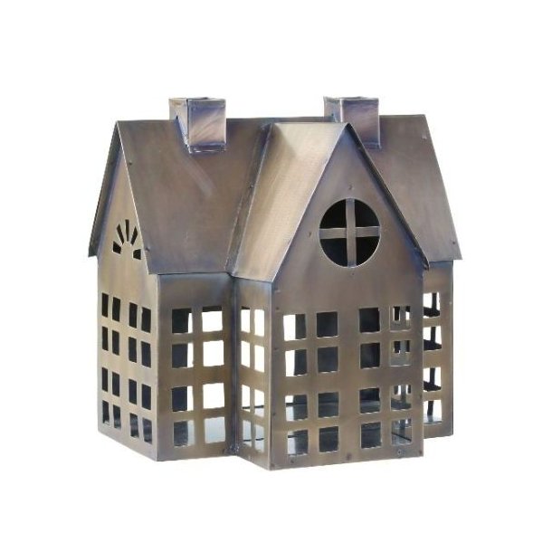 Et fritlagt produktbillede p� en ren hvid baggrund af en detaljeret metal lanterne formet som et hus i antik messingfinish. Huset har et distinkt patineret udseende med en blanding af messing og kobber toner, to skorstene, og et komplekst netv�rk af firkantede vinduer og en rund central cross-rude.
