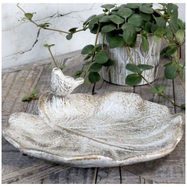 N�rbillede af bladformet fuglebad i creme-hvid med guld patina, der viser overfladens struktur og detaljer.