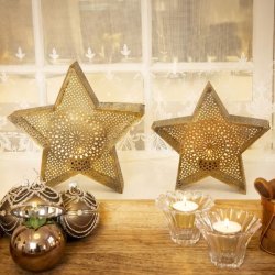 To m�nstrede julestjerner i antik guld metal som fyrfadsholdere placeret i en vindueskarm sammen med julekugler og glasstager.