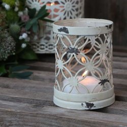 Fyrfadsstage i jern og glas med creme hvid patina opstillet i et hyggeligt milj� med t�ndt lys p� et tr�bord.