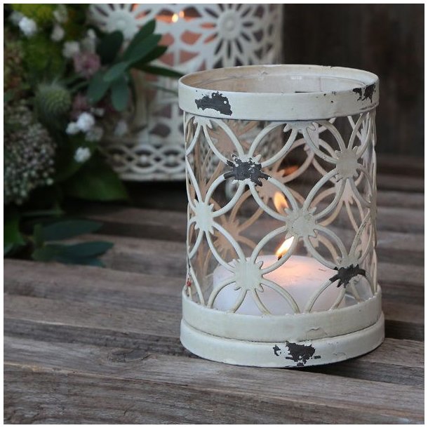Fyrfadsstage i jern og glas med creme hvid patina opstillet i et hyggeligt milj� med t�ndt lys p� et tr�bord.