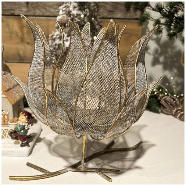Blomsterformet fyrfadsstage p� grenfod i antik guld metal opstillet i et hyggeligt julemilj�.