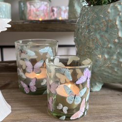N�rbillede af to t�ndte sommerfugle-fyrfadsstager i lysegr�nt glas med forskellige m�nstre.