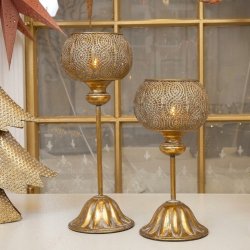 Kvadratisk milj�billede af to h�je fyrfadsstager p� fod i antik guld metal placeret p� et d�kket bord.
