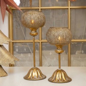 Kvadratisk milj�billede af to h�je fyrfadsstager p� fod i antik guld metal placeret p� et d�kket bord.