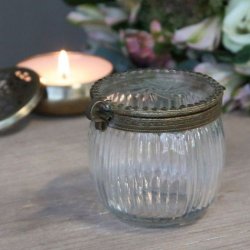 Den riflede glaskrukke med messingdekoration vist i et hyggeligt milj� ved siden af et t�ndt lys.