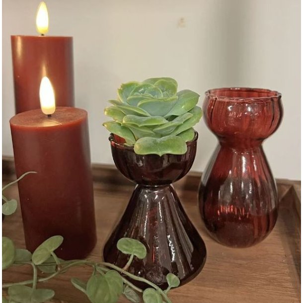To bordeauxr�de glasvaser i forskellige st�rrelser brugt som hyacintglas og fyrfadsstage p� et bord