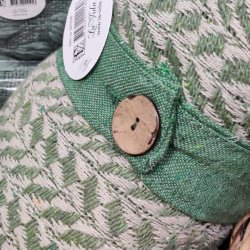 N�rbillede af det praktiske lukkeb�nd med knap, der holder den sammenrullede gr�nne bomuldsplaid p� plads.