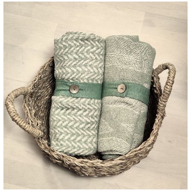 En sammenrullet gr�n plaid holdt p� plads af et praktisk b�nd med knap, klar til transport.