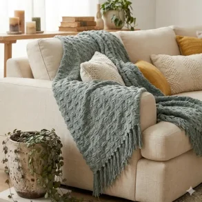 Milj�billede af den gr�nne plaid draperet over en lys sofa, hvilket viser m�nsterets spil i et naturligt lys.