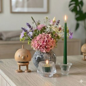 En hyggelig opstilling p� en lys tr�sk�nk med en Hoptimist-figur i egetr�, en vase med hortensia og lavendel, samt t�ndte stearinlys i glasstager.