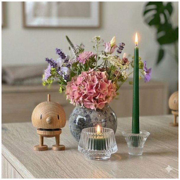 En hyggelig opstilling p� en lys tr�sk�nk med en Hoptimist-figur i egetr�, en vase med hortensia og lavendel, samt t�ndte stearinlys i glasstager.