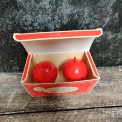 To r�de Hoptimist jubil�umsfigurer med en h�jde p� 6,5 cm og diameter p� 5 cm, set oppefra i en �ben, r�d jubil�ums�ske, der st�r p� en m�rk tr�overflade mod en rustik baggrund.