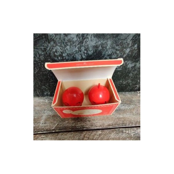To r�de Hoptimist jubil�umsfigurer med en h�jde p� 6,5 cm og diameter p� 5 cm, set oppefra i en �ben, r�d jubil�ums�ske, der st�r p� en m�rk tr�overflade mod en rustik baggrund.